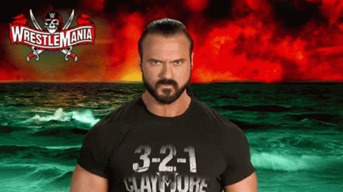 a man in a wrestlemania shirt stands in front of a ocean