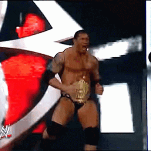 A Man In A Wrestling Outfit Is Holding A Wrestling Belt GIF