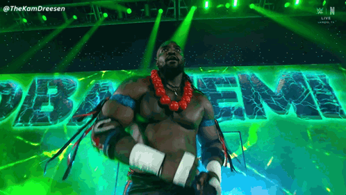 A Man In A Wrestling Outfit Is Standing In Front Of A Green Sign That Says " Baem " GIF
