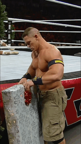 A Man In A Wrestling Ring Is Wrapping A Gift With A Bow GIF