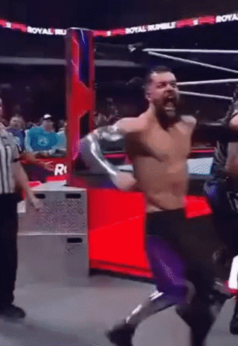 A Man In A Wrestling Ring With A Referee And A Sign That Says Royal Rumble On It GIF