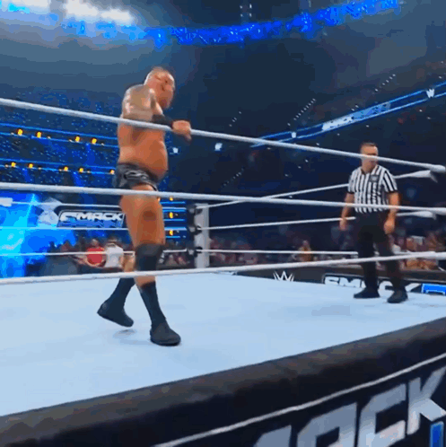 A Man In A Wrestling Ring With A Referee And A Sign That Says Smack GIF