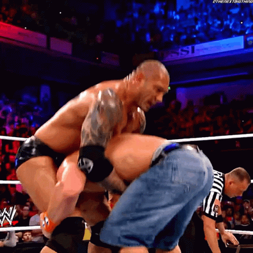 A Man In A Wrestling Ring With A Referee That Says ' Ric ' On His Shorts GIF