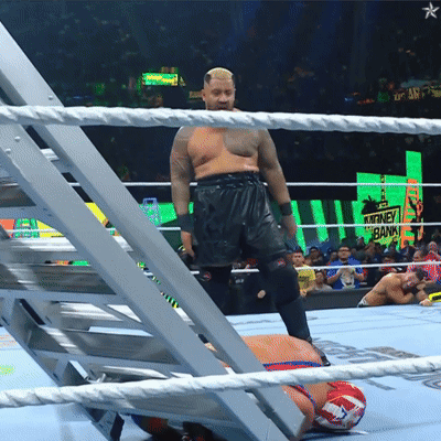 A Man In A Wrestling Ring With A Sign That Says Money Bank In The Background GIF