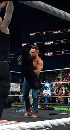 A Man In A Wrestling Ring With The Words Raw On The Walls GIF