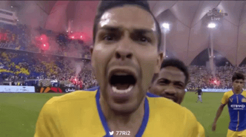 A Man In A Yellow And Blue Jersey Is Screaming At The Camera GIF