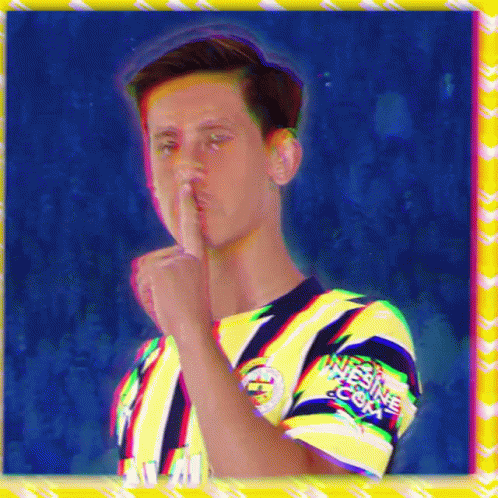 A Man In A Yellow And Blue Shirt Has His Finger To His Mouth And The Word Nitesine.com Is On His Sleeve GIF