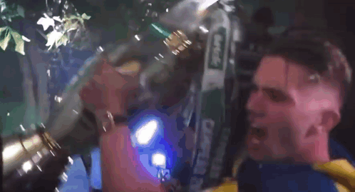 A Man In A Yellow And Blue Shirt Is Holding A Large Trophy In His Mouth GIF