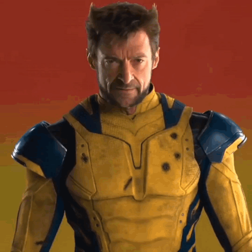 A Man In A Yellow And Blue Superhero Costume Looks At The Camera GIF