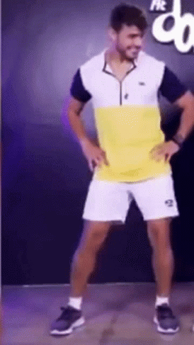 A Man In A Yellow And White Shirt And Shorts Is Dancing GIF