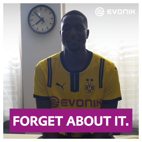 A Man In A Yellow Evonik Shirt Is Smiling In Front Of A Clock GIF