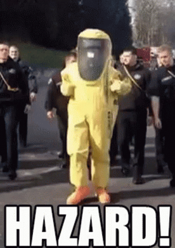 A Man In A Yellow Hazmat Suit Is Walking Down A Street Surrounded By Police Officers .. GIF