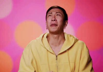A Man In A Yellow Hoodie Is Crying With His Hands Folded In Front Of His Face GIF
