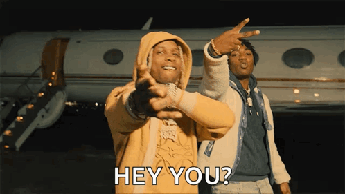A Man In A Yellow Hoodie Is Pointing At Another Man In Front Of An Airplane And Says Hey You GIF