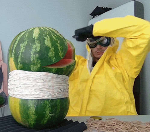A Man In A Yellow Jacket Is Cutting A Watermelon With A Knife GIF