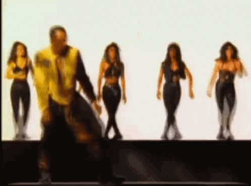 A Man In A Yellow Jacket Is Dancing With Three Women In Black Clothes . GIF