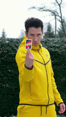 A Man In A Yellow Jacket Is Holding A Uno Card GIF
