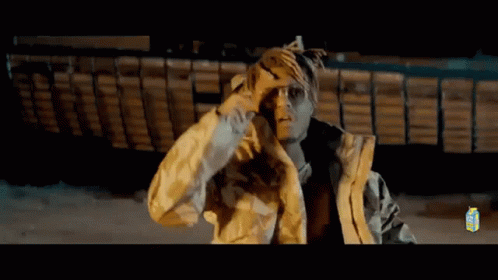 A Man In A Yellow Jacket Is Standing In Front Of A Boat . GIF