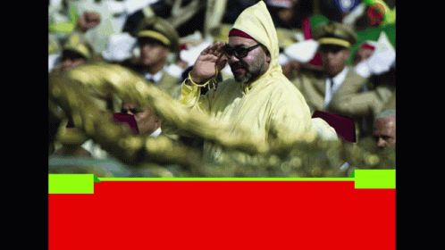 A Man In A Yellow Jacket Salutes In Front Of A Crowd Of People GIF