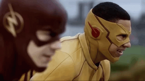 A Man In A Yellow Mask Is Standing Next To Another Man In A Red Mask . GIF