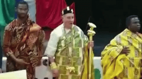 A Man In A Yellow Robe Is Standing Next To Two Other Men In Traditional Clothing . GIF