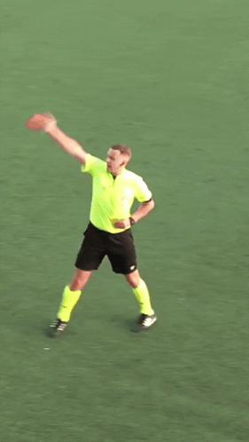 A Man In A Yellow Shirt And Black Shorts Is Holding A Frisbee In His Hand GIF