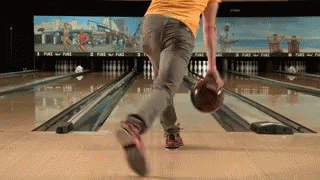 A Man In A Yellow Shirt Is Bowling On A Bowling Alley GIF