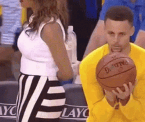 A Man In A Yellow Shirt Is Holding A Basketball In Front Of A Woman In A White Top . GIF