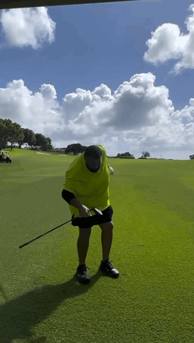 A Man In A Yellow Shirt Is Holding A Golf Club GIF