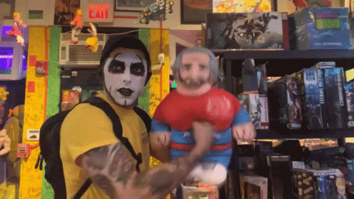 A Man In A Yellow Shirt Is Holding A Stuffed Superman Figure GIF