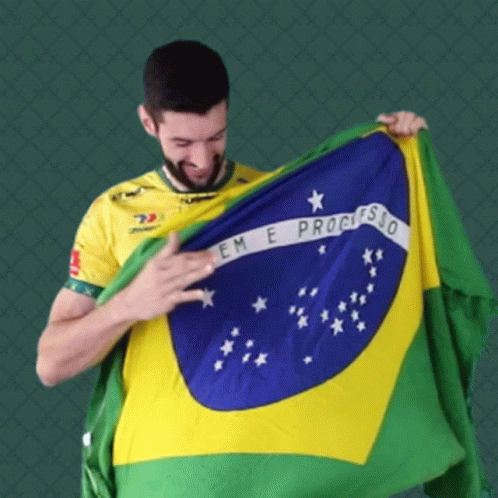 a man in a yellow shirt is holding up a flag that says em e progresso