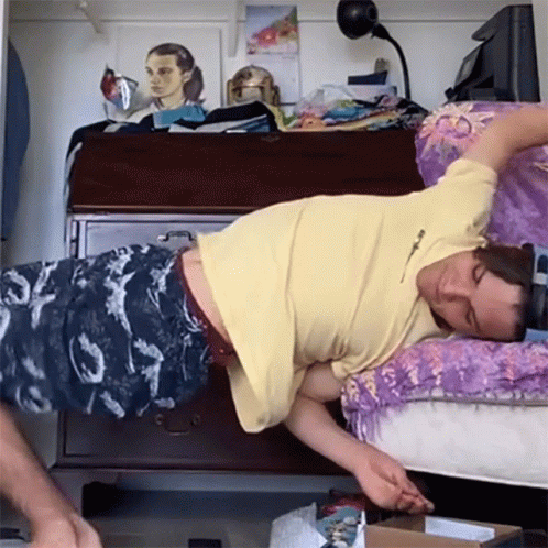 A Man In A Yellow Shirt Is Laying On His Back GIF