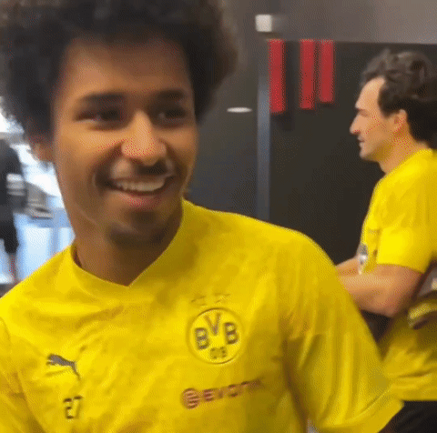 a man in a yellow shirt is smiling in a room .