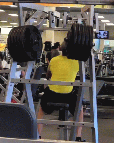 A Man In A Yellow Shirt Is Squatting On A Machine GIF