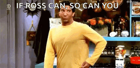 A Man In A Yellow Shirt Is Standing In A Kitchen With His Hand On His Hips . GIF