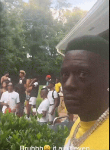A Man In A Yellow Shirt Is Standing In Front Of A Crowd Of People GIF