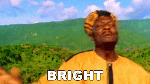 a man in a yellow shirt is standing in front of a mountain with the word bright written on his chest .