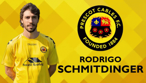 A Man In A Yellow Shirt Is Standing In Front Of A Prescot Cables Fc Logo GIF