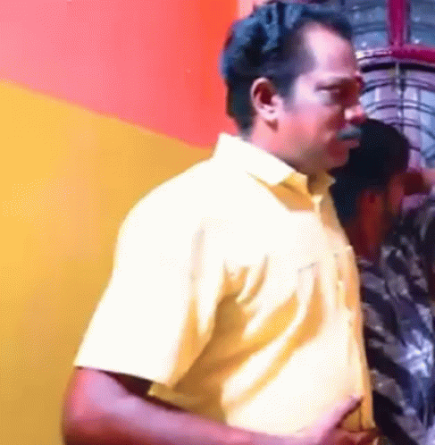 A Man In A Yellow Shirt Is Standing Next To Another Man GIF