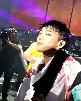 A Man In A Yellow Shirt Is Taking A Picture Of A Man In A White Shirt With Blood On His Shirt GIF