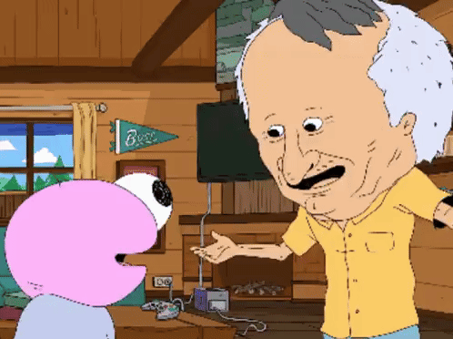 A Man In A Yellow Shirt Is Talking To A Pink Flamingo In A Living Room With A Banner That Says Buzz GIF