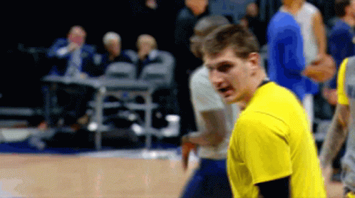 A Man In A Yellow Shirt Stands On A Basketball Court With Other Players GIF