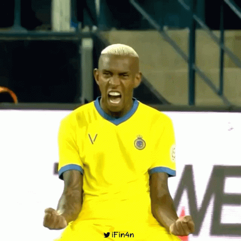A Man In A Yellow Shirt With The Letter V On The Front GIF