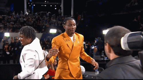 A Man In A Yellow Suit Talks To A Man In A White Suit GIF