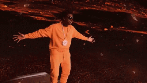 A Man In A Yellow Tracksuit Is Standing In Front Of A Green Background GIF