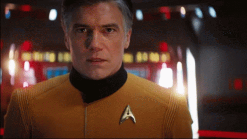 A Man In A Yellow Uniform With A Star Trek Badge GIF