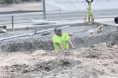 A Man In A Yellow Vest Is Crawling Through A Hole In The Dirt GIF