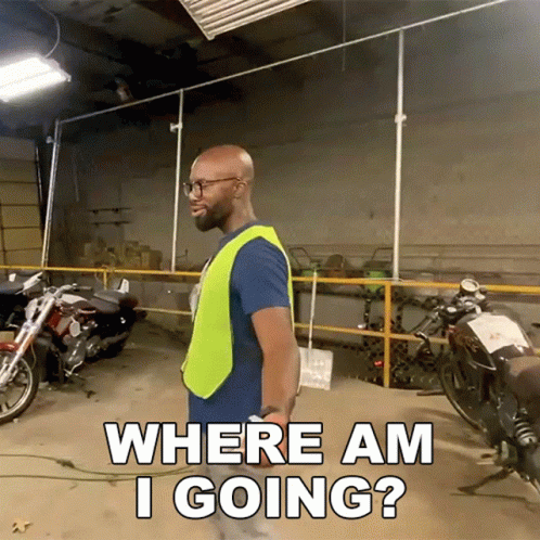 a man in a yellow vest is standing in a garage with motorcycles and asking where am i going