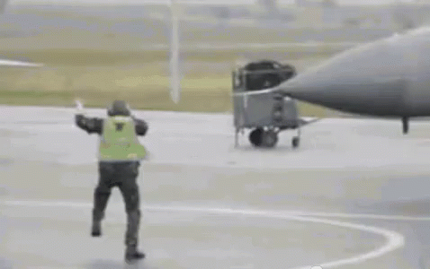 Man In Yellow Vest Next To Fighter Jet GIF