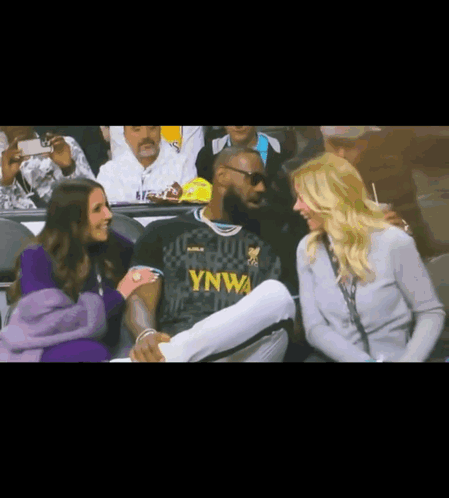 A Man In A Ynwa Jersey Sits In The Stands With Two Women GIF